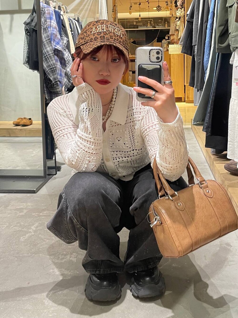 ブラック系のブーツ、ブラウン系のボストンバッグ、ブラック系のデニムパンツを着用したレディースの春コーディネートの3枚目の写真