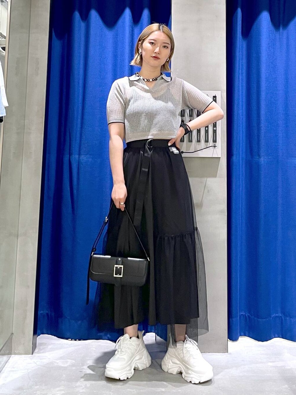 ホワイト系のスニーカー、ブラック系のハンドバッグ、ブラック系のニット/セーターを着用したレディースの夏コーディネートの2枚目の写真