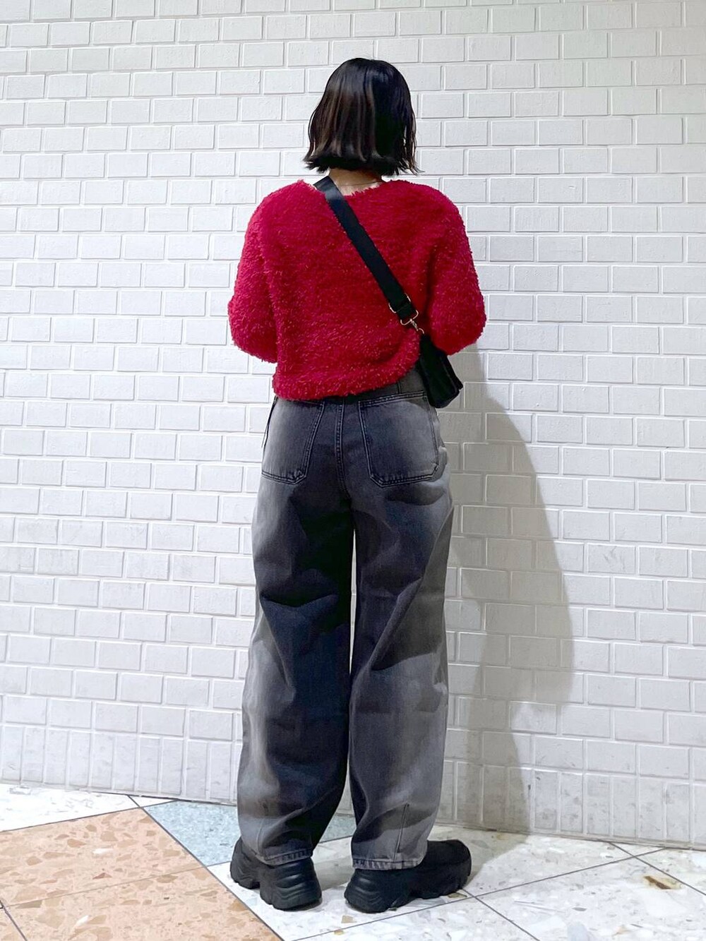 ブラック系のデニムパンツ、ブラック系のブーツ、ブラック系のショルダーバッグを着用したレディースの秋コーディネートの5枚目の写真