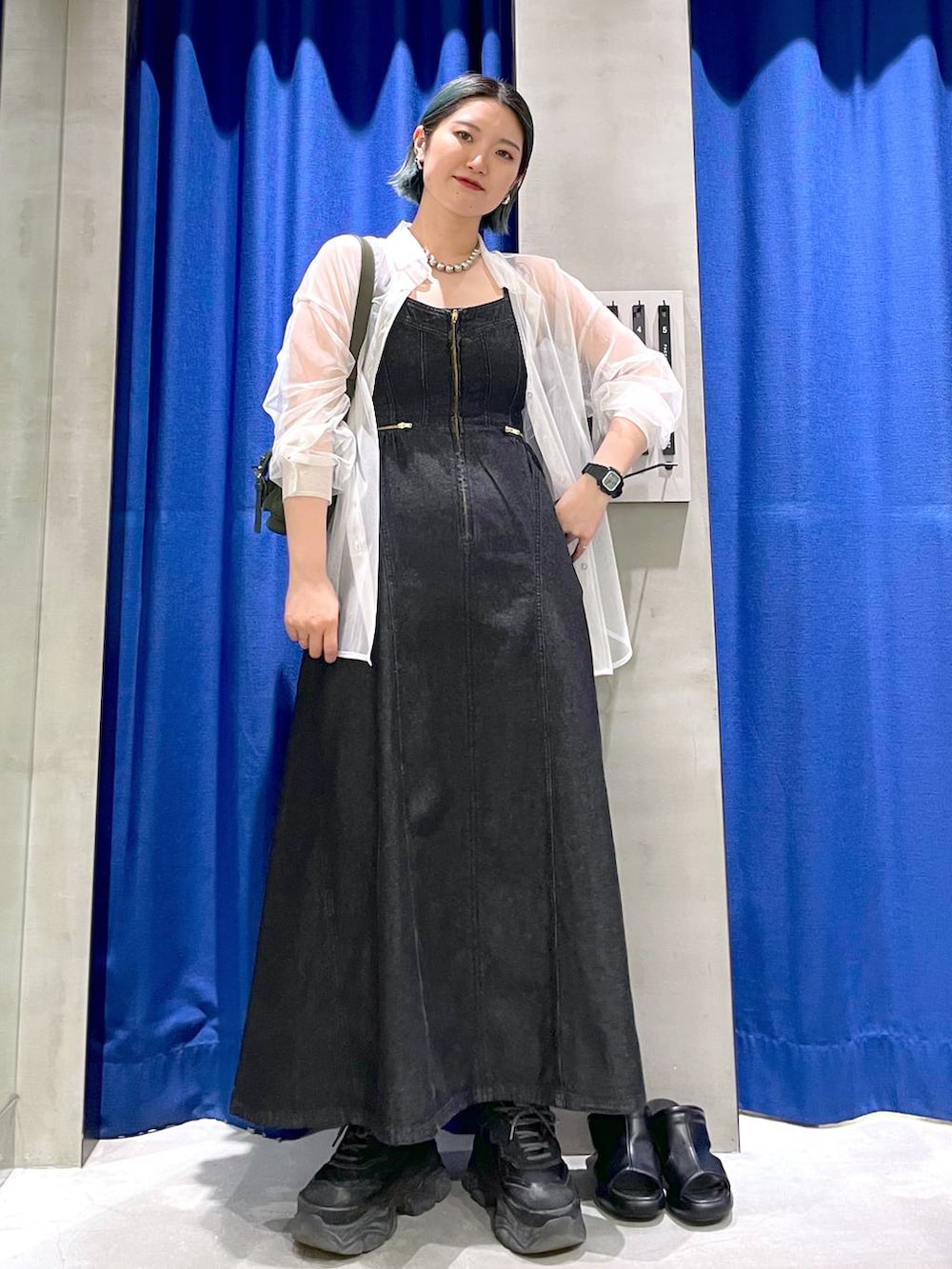 グリーン系のショルダーバッグ、ブラック系のスニーカー、ブラック系のワンピースを着用したレディースの春コーディネートの5枚目の写真