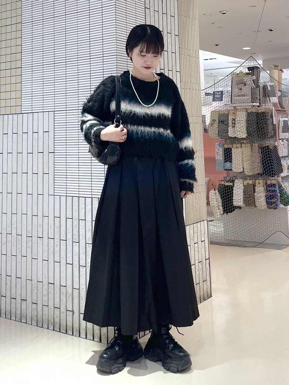 ブラック系のブーツ、ブラック系のスカート、ブラック系のショルダーバッグを着用したレディースの冬コーディネートの3枚目の写真