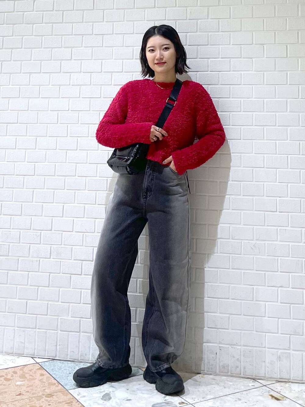 ブラック系のデニムパンツ、ブラック系のブーツ、ブラック系のショルダーバッグを着用したレディースの秋コーディネートの2枚目の写真