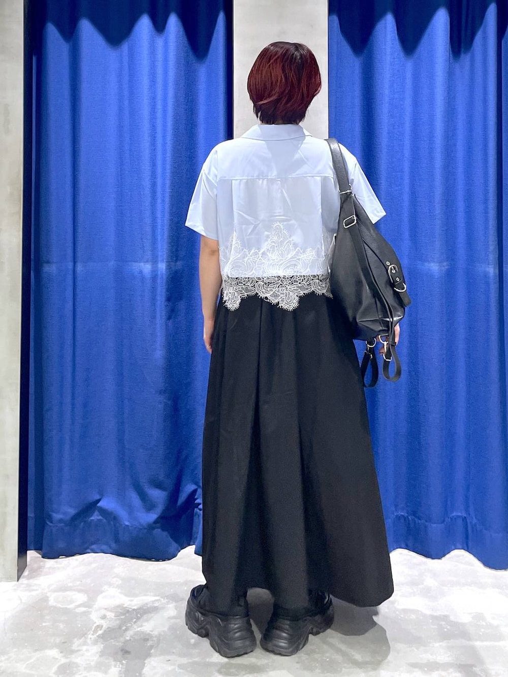 ブラック系のショルダーバッグ、ブラック系のジャンパースカート、ブラック系のスニーカーを着用したレディースの夏コーディネートの3枚目の写真