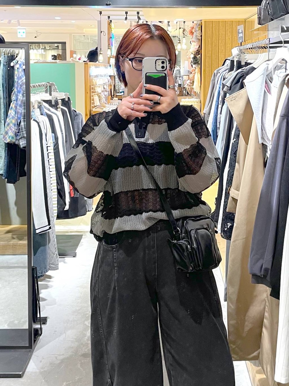 ブラック系のブーツ、ブラック系のデニムパンツ、ブラック系のショルダーバッグを着用したレディースの春コーディネートの2枚目の写真