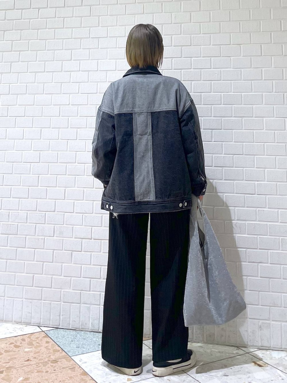 ブラック系のスラックス、グレー系のニット/セーター、ブラック系のデニムジャケットを着用したレディースの春コーディネートの3枚目の写真