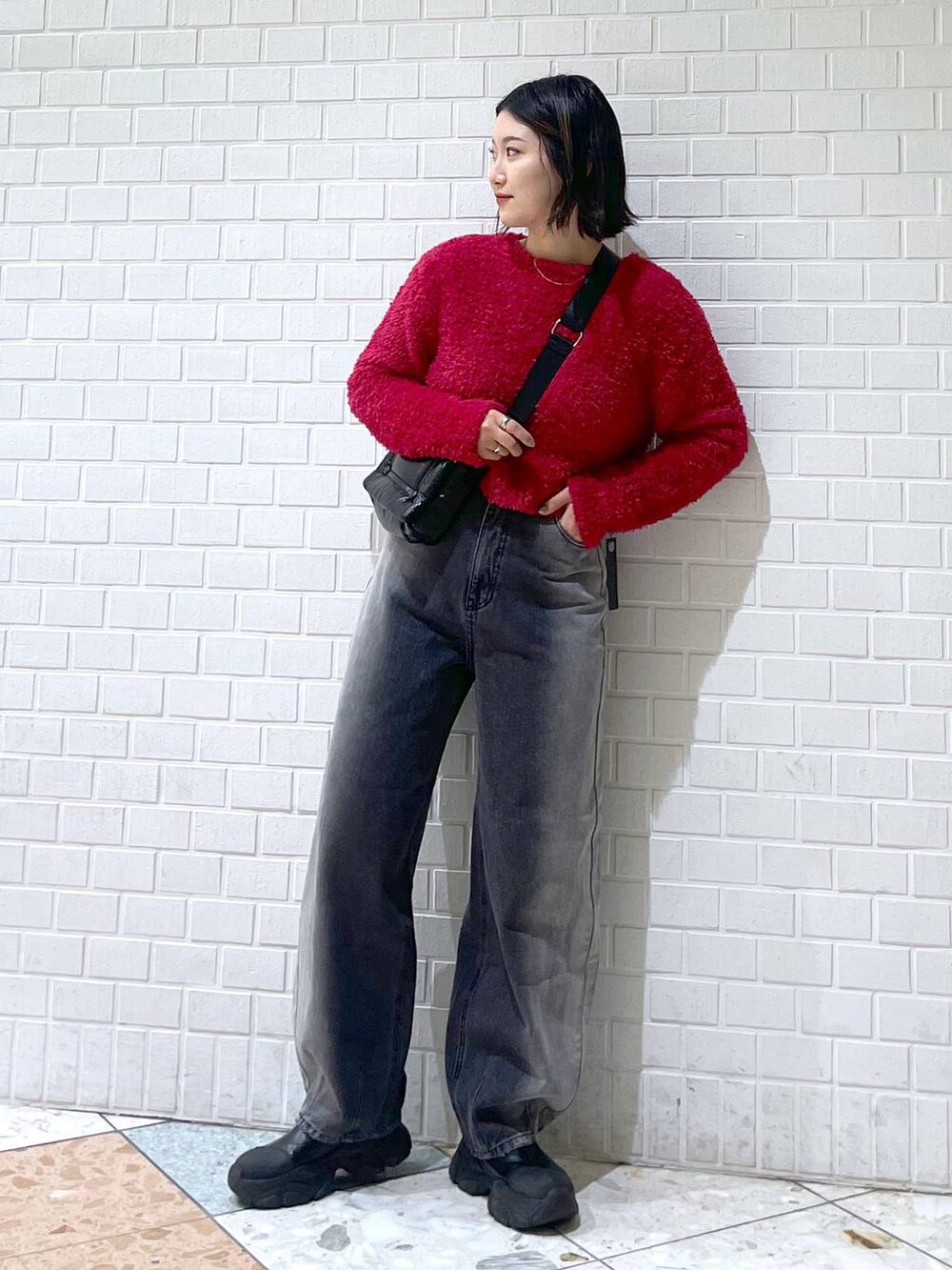 ブラック系のデニムパンツ、ブラック系のブーツ、ブラック系のショルダーバッグを着用したレディースの秋コーディネートの3枚目の写真