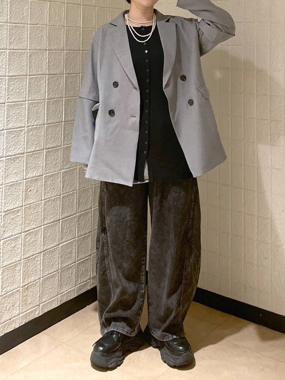 ブラック系のブーツ、グレー系のテーラードジャケット、ブラック系のデニムパンツを着用したレディースの春コーディネートの3枚目の写真