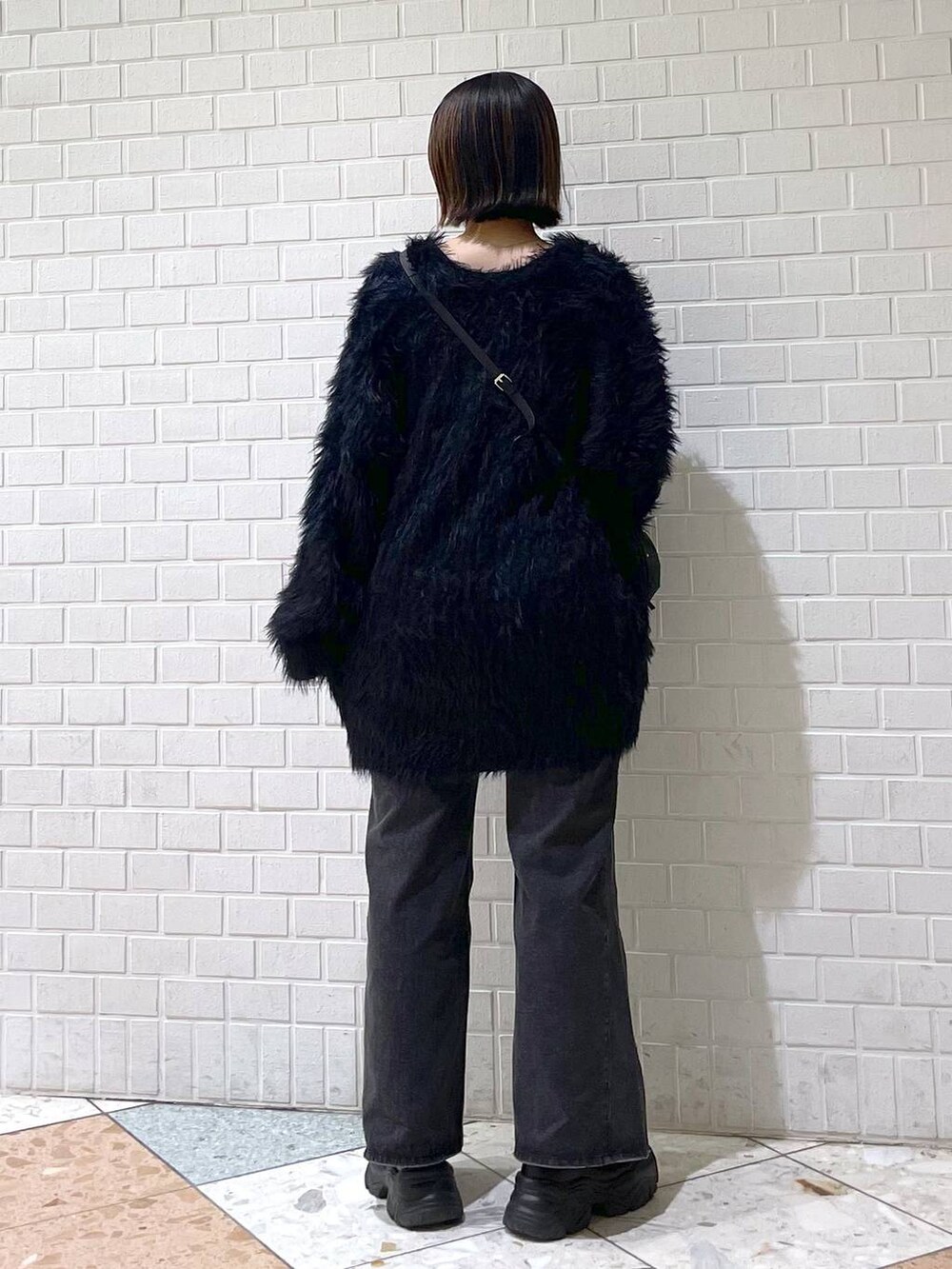 ブラック系のタンクトップ、ブラック系のデニムパンツ、ブラック系のブーツを着用したレディースの秋コーディネートの3枚目の写真