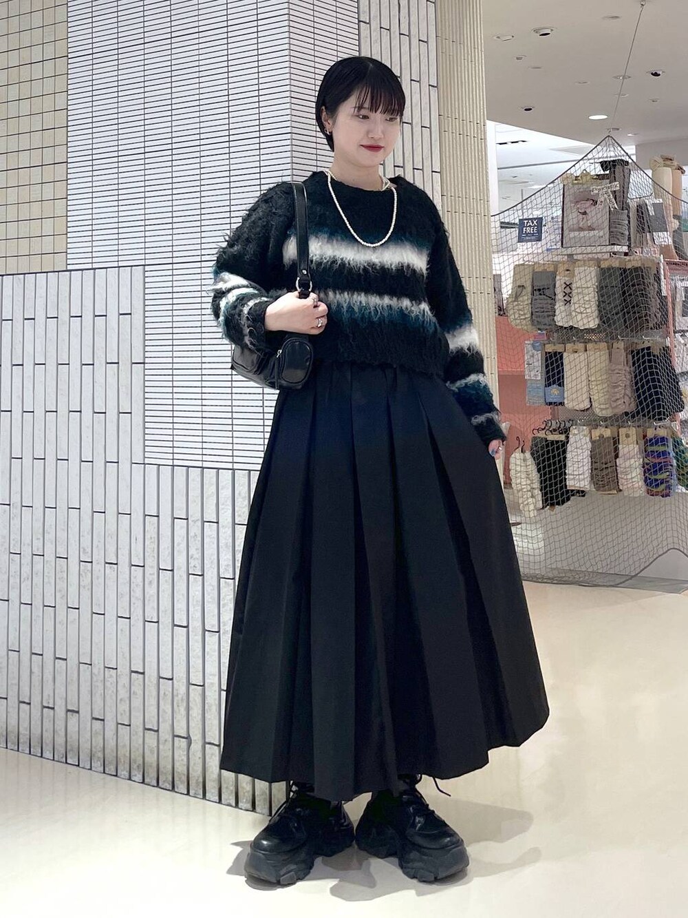 ブラック系のブーツ、ブラック系のスカート、ブラック系のショルダーバッグを着用したレディースの冬コーディネートの2枚目の写真