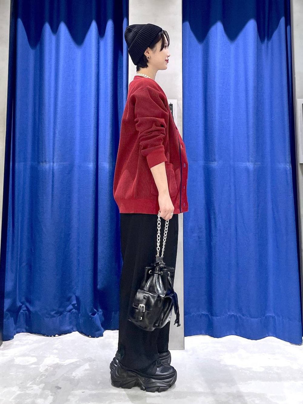 ブラック系のスニーカー、ブラック系のショルダーバッグ、レッド系のカーディガン/ボレロを着用したレディースの秋コーディネートの4枚目の写真