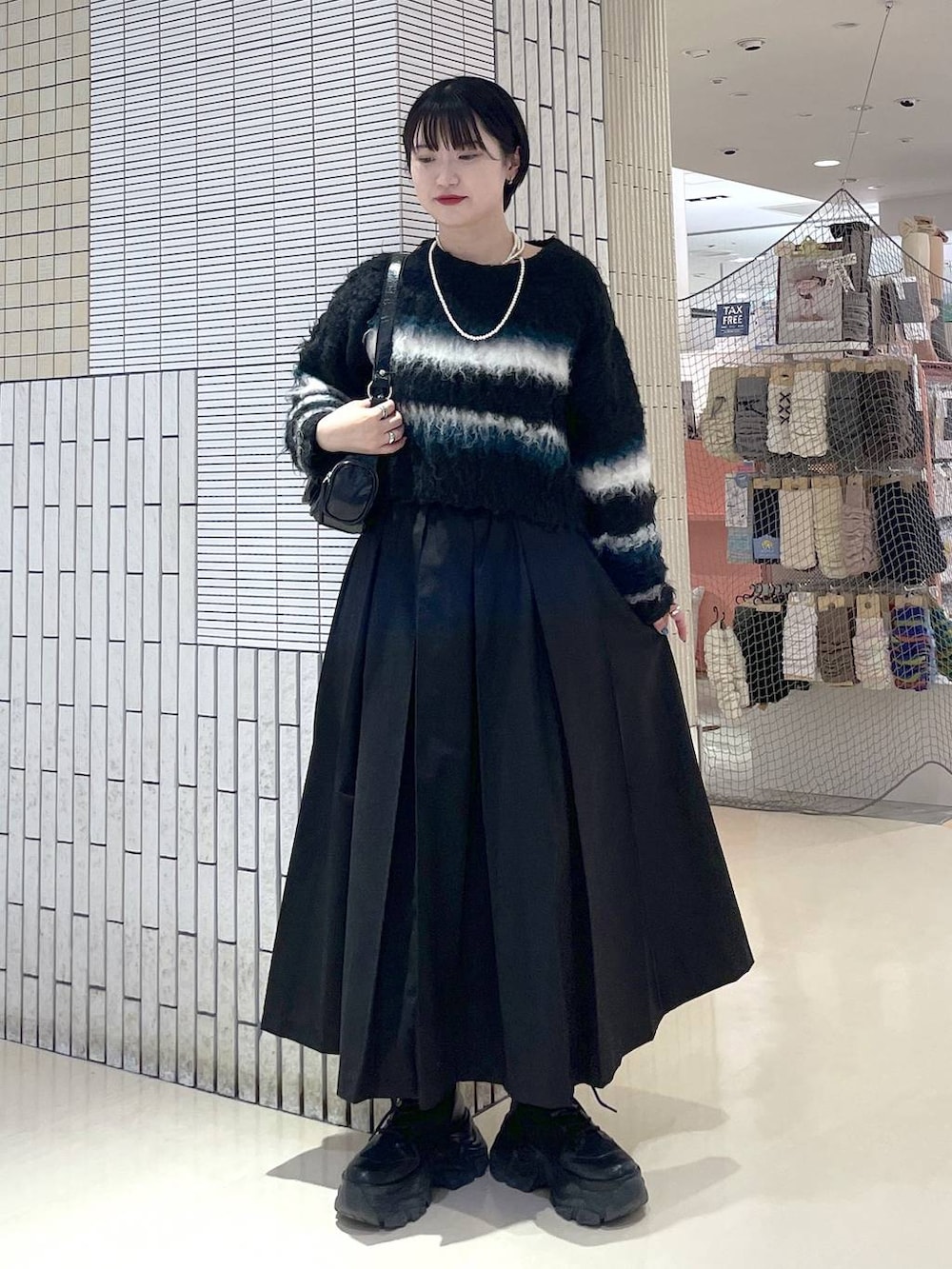 ブラック系のブーツ、ブラック系のスカート、ブラック系のショルダーバッグを着用したレディースの冬コーディネートの4枚目の写真