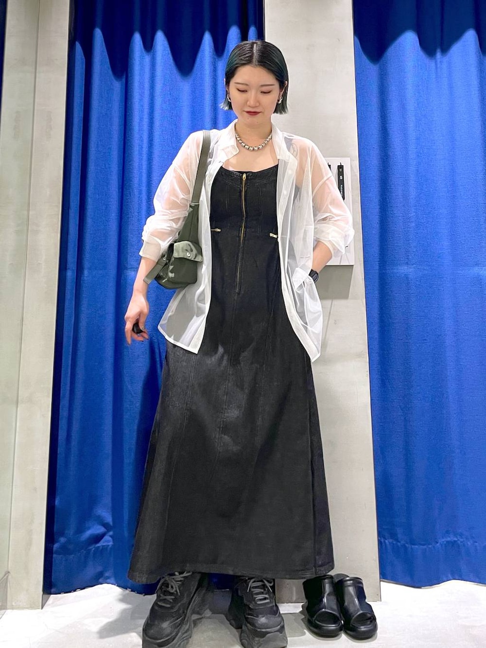 グリーン系のショルダーバッグ、ブラック系のスニーカー、ブラック系のワンピースを着用したレディースの春コーディネートの4枚目の写真