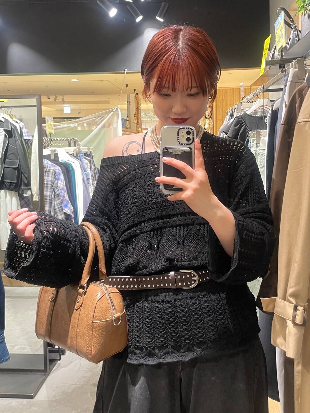 ブラック系のブーツ、ブラウン系のボストンバッグ、ブラック系のデニムパンツを着用したレディースの春コーディネートの4枚目の写真