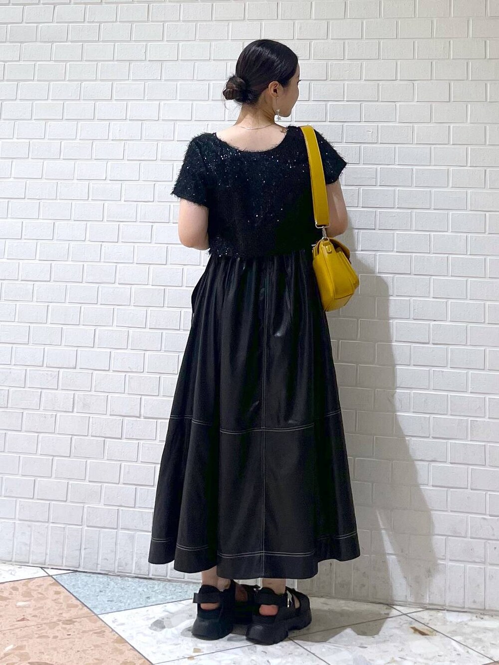 ブラック系のサンダル、ブラック系のワンピース、イエロー系のショルダーバッグを着用したレディースの夏コーディネートの2枚目の写真