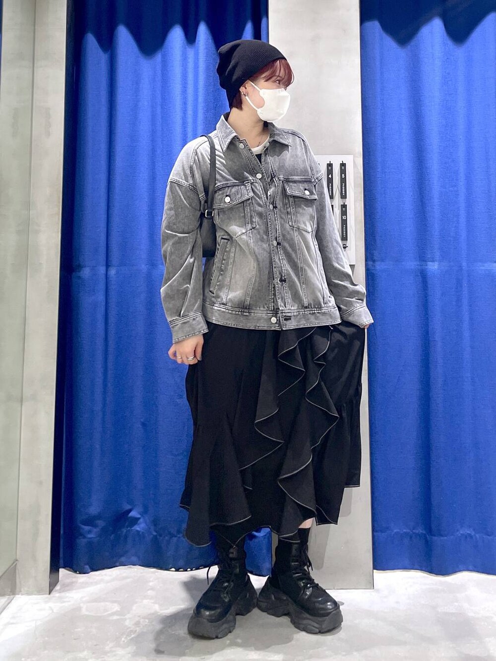 ブラック系のブーツ、ブラック系のスカート、ブラック系のハンドバッグを着用したレディースの冬コーディネートの3枚目の写真