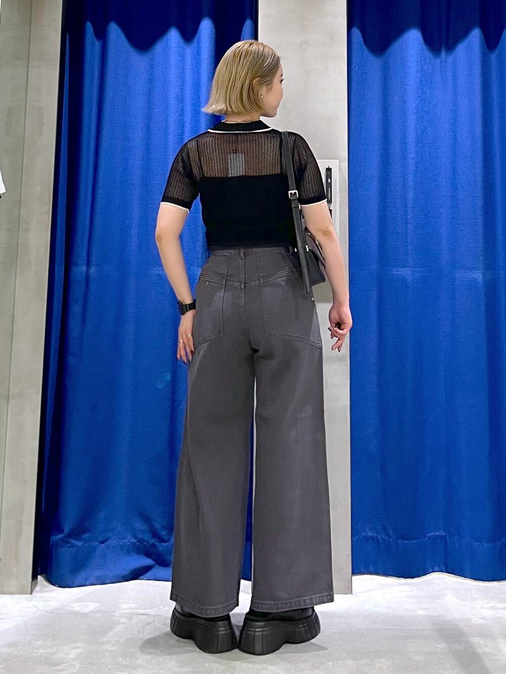 ブラック系のスニーカー、ブラック系のハンドバッグ、ブラック系のデニムパンツを着用したレディースの夏コーディネートの4枚目の写真