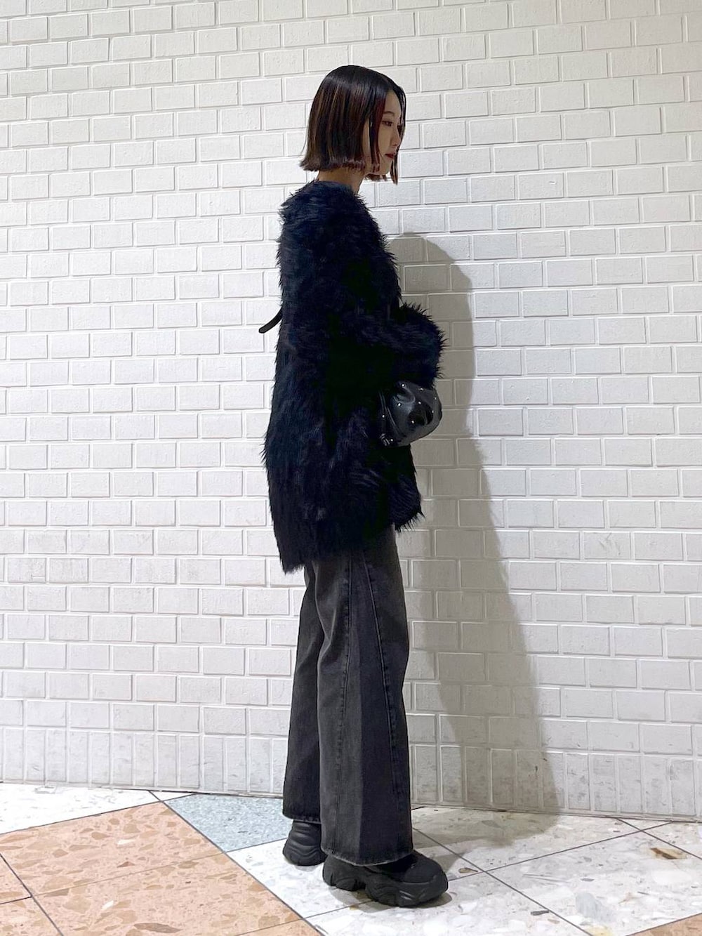 ブラック系のタンクトップ、ブラック系のデニムパンツ、ブラック系のブーツを着用したレディースの秋コーディネートの2枚目の写真