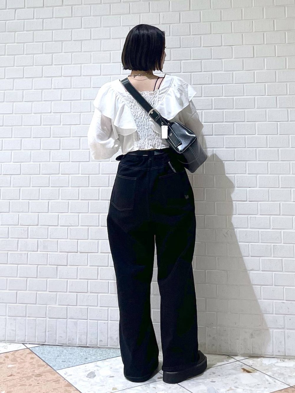 ブラック系のサンダル、ブラック系のその他パンツ、ホワイト系のシャツ/ブラウスを着用したレディースの秋コーディネートの2枚目の写真