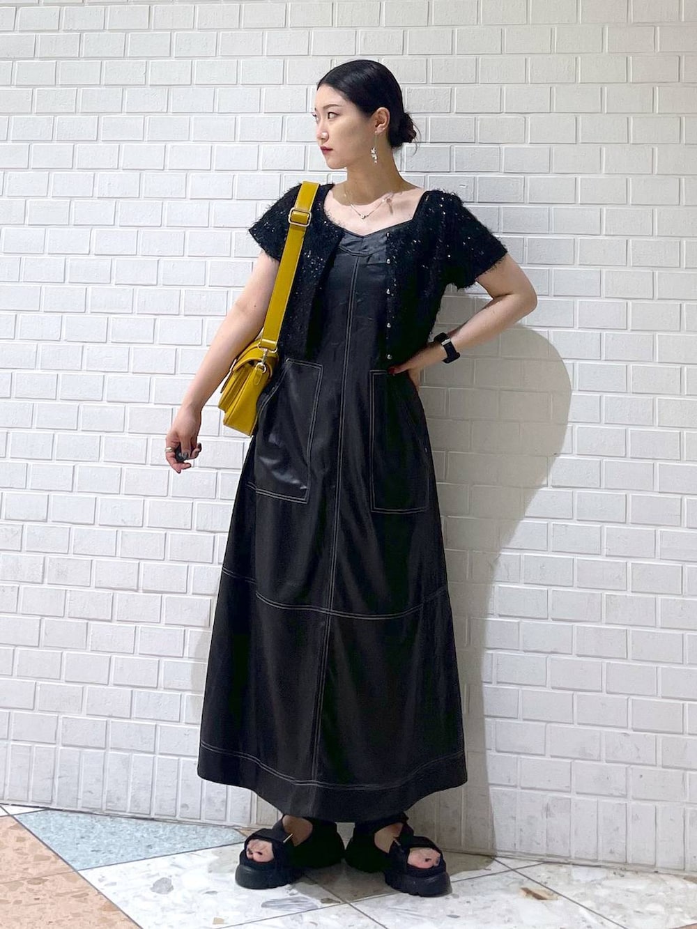 ブラック系のサンダル、ブラック系のワンピース、イエロー系のショルダーバッグを着用したレディースの夏コーディネートの3枚目の写真