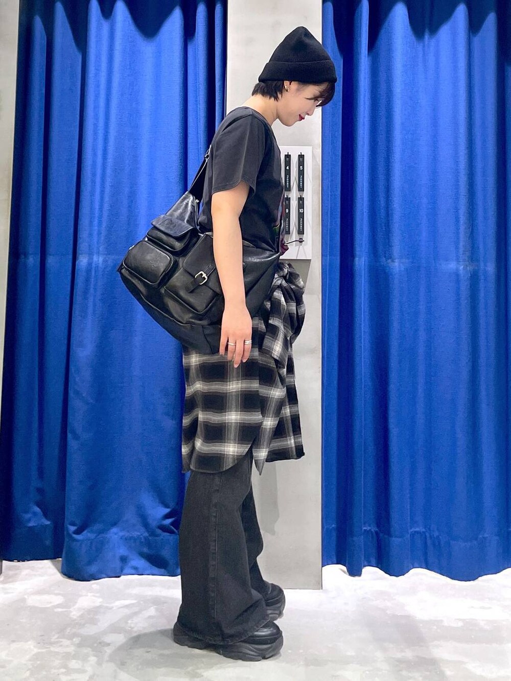 ブラック系のスニーカー、ブラック系のデニムパンツ、ブラック系のショルダーバッグを着用したレディースの秋コーディネートの4枚目の写真