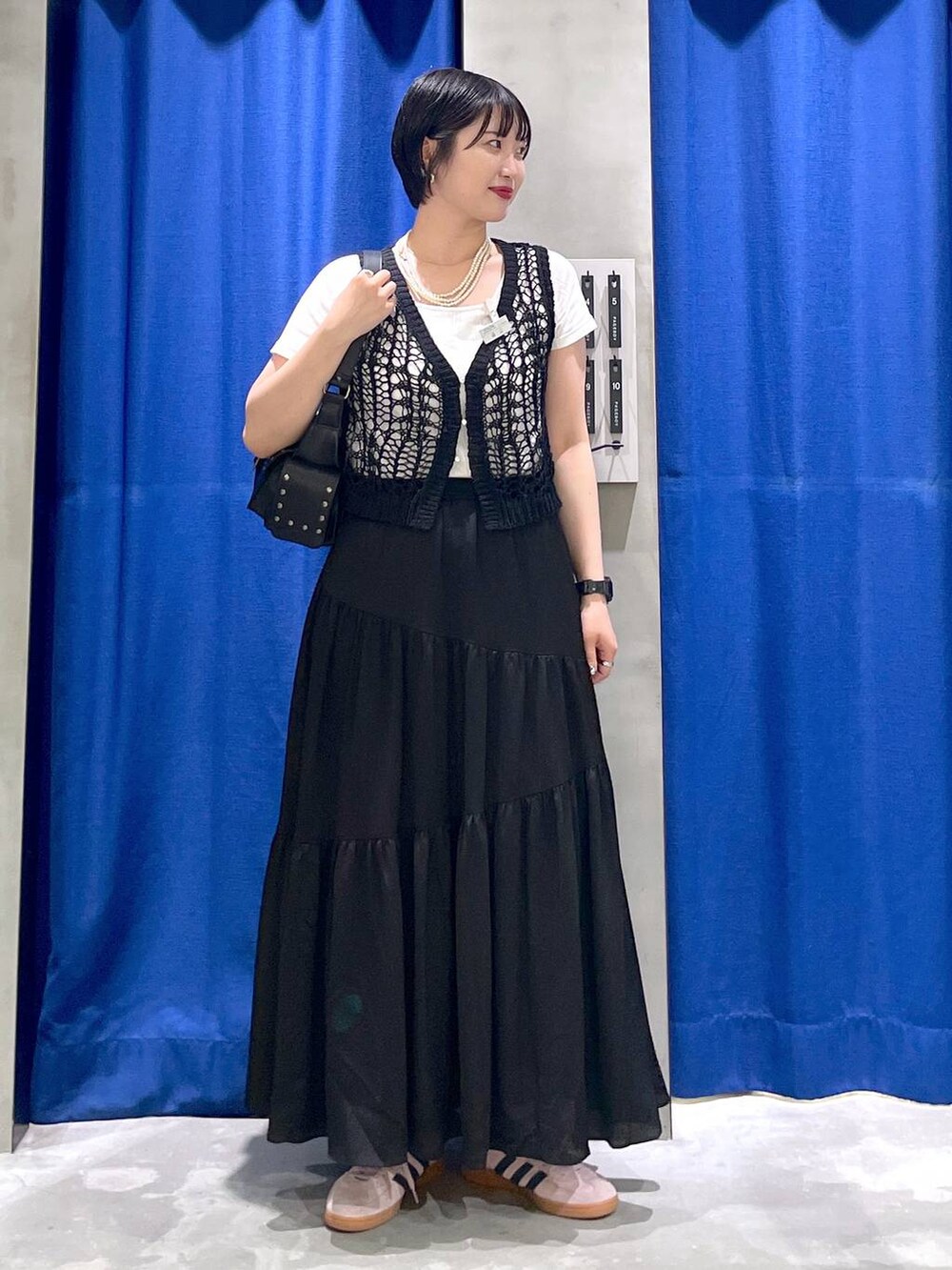 ブラック系のスカート、ブラック系のショルダーバッグ、ブラック系のTシャツ/カットソーを着用したレディースの夏コーディネートの2枚目の写真