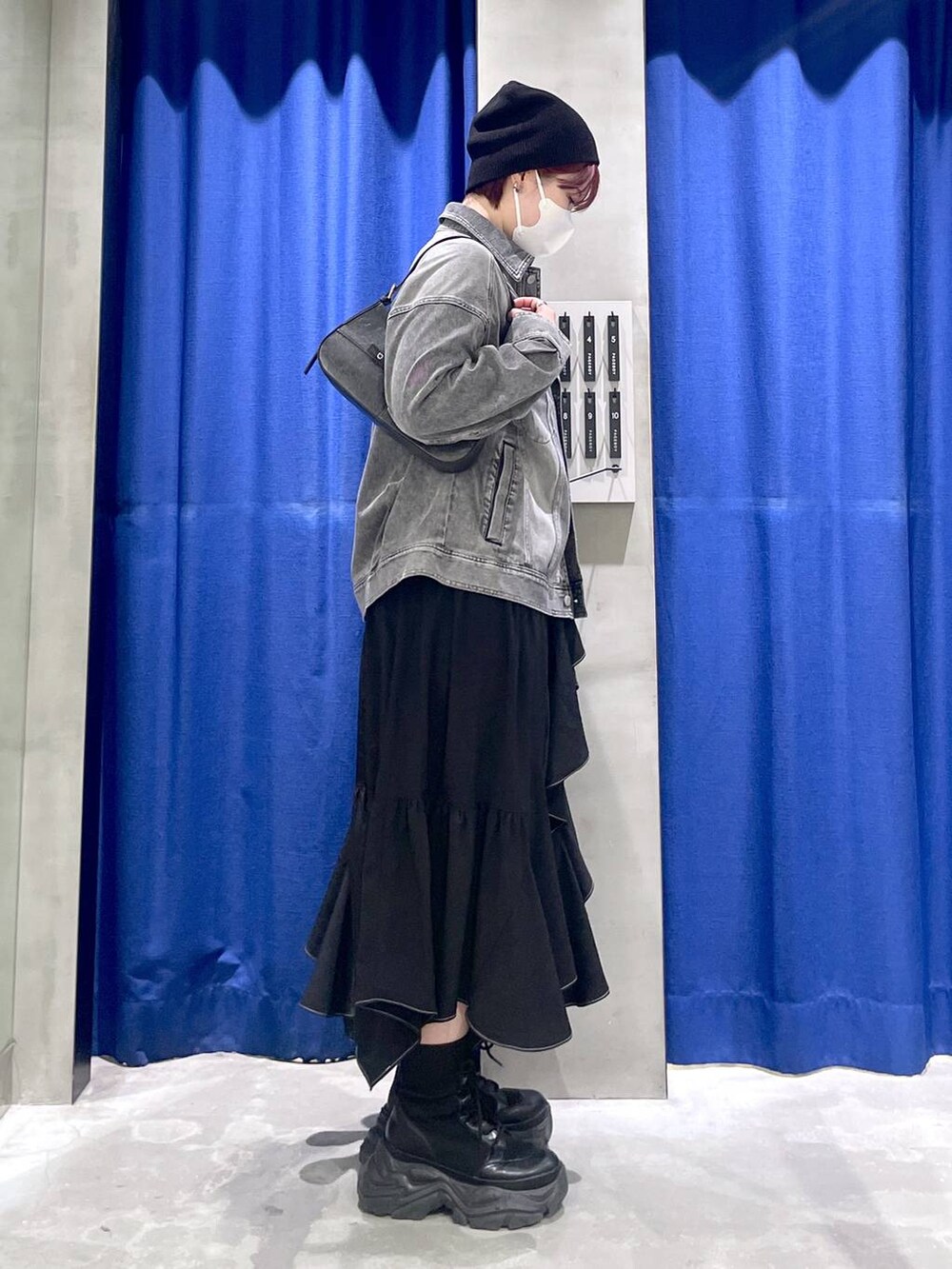 ブラック系のブーツ、ブラック系のスカート、ブラック系のハンドバッグを着用したレディースの冬コーディネートの4枚目の写真