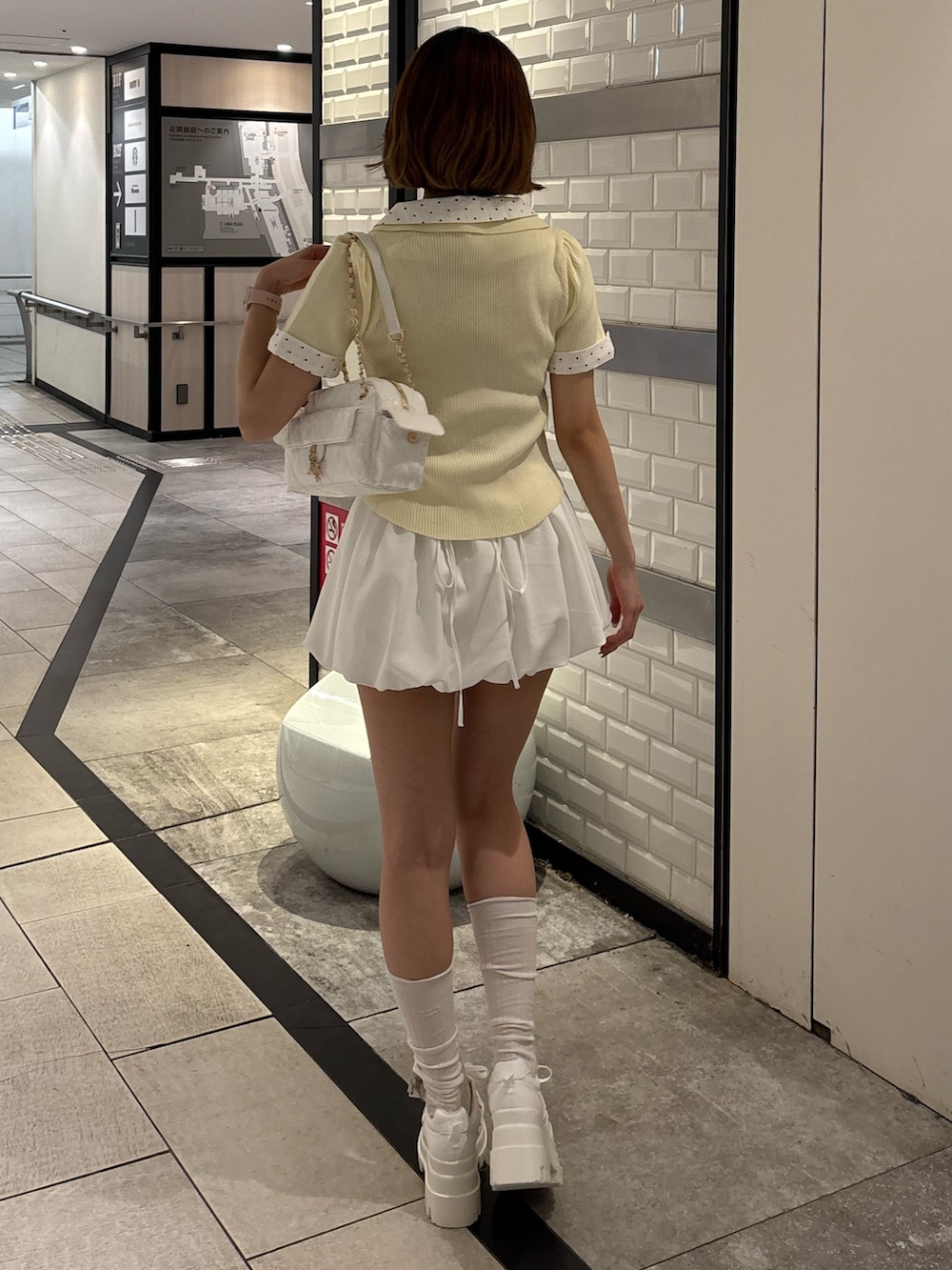 イエロー系のニット/セーター、ブラック系のニット/セーター、ブラック系のスカートを着用したレディースの夏コーディネートの3枚目の写真