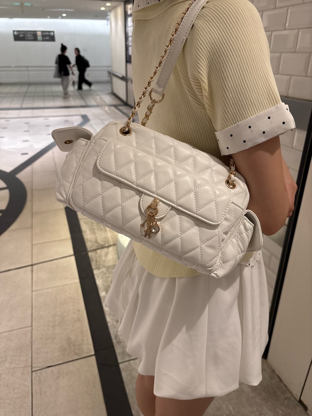 イエロー系のニット/セーター、ブラック系のニット/セーター、ブラック系のスカートを着用したレディースの夏コーディネートの4枚目の写真