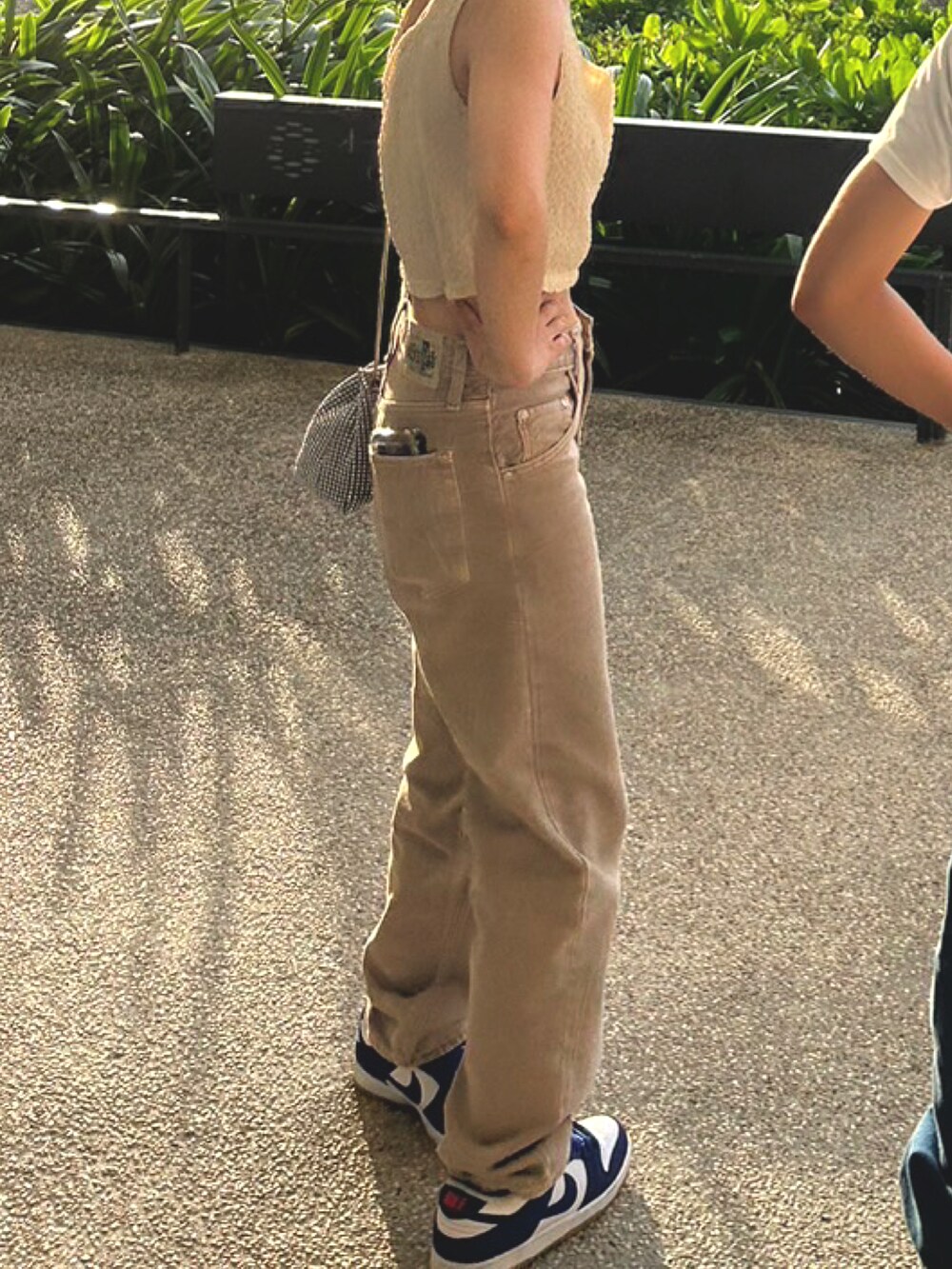 ベージュ系のトップス、ベージュ系のデニムパンツ、シルバー系のショルダーバッグを着用したレディースの秋コーディネートの2枚目の写真