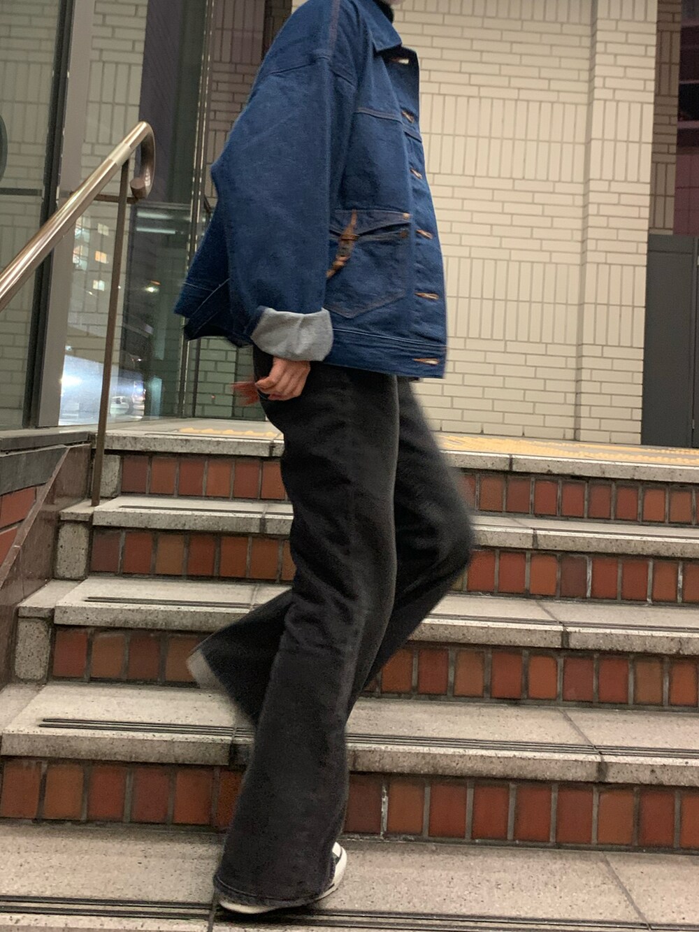 ブラック系のニット/セーター、ブルー系のデニムジャケット、ブラック系のデニムパンツを着用したレディースの春コーディネートの2枚目の写真