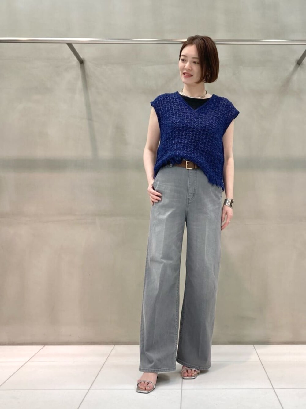 グレー系のデニムパンツ、ブルー系のニット/セーター、シルバー系のブレスレットを着用したレディースの春コーディネートの7枚目の写真