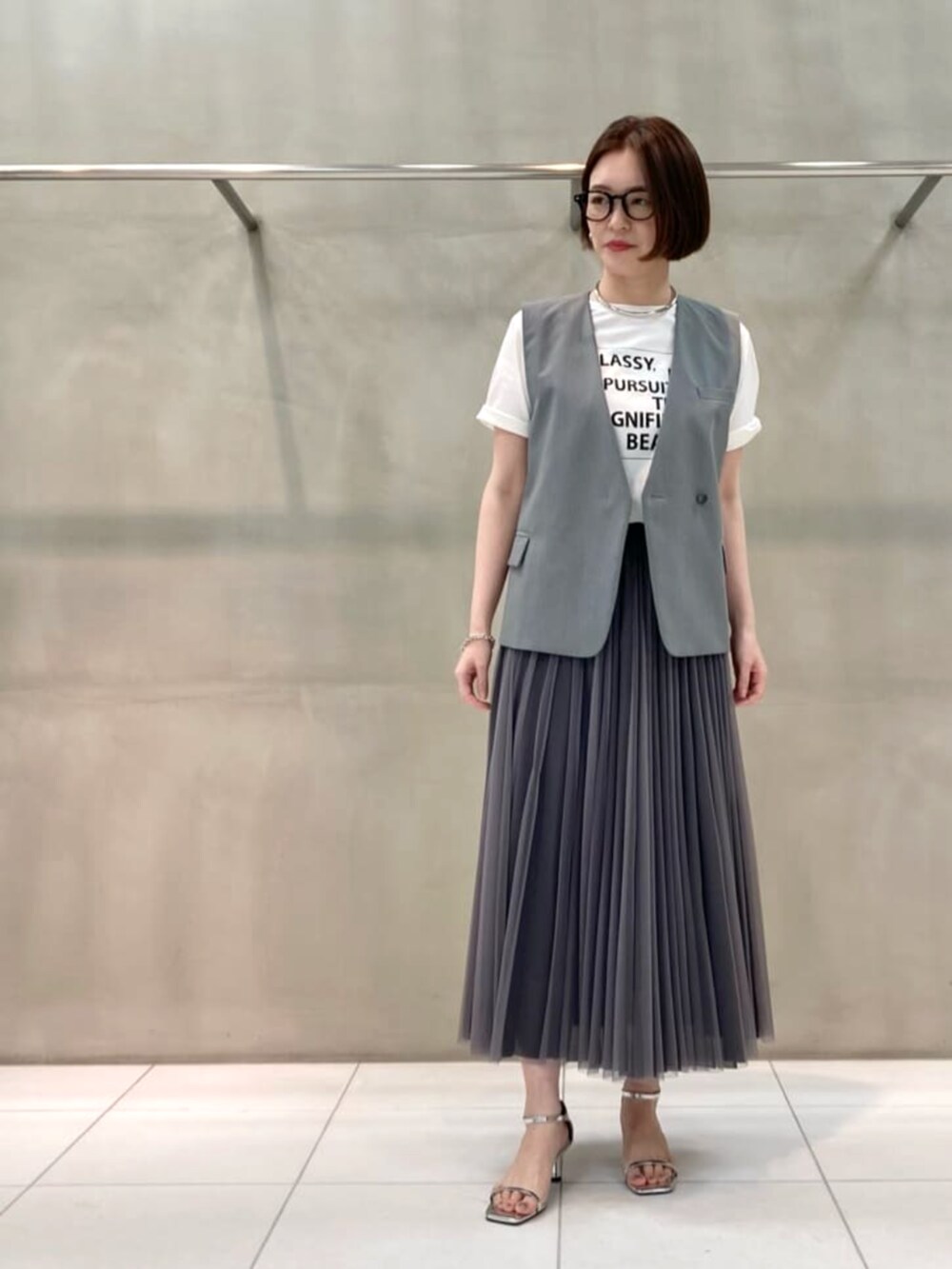 ブルー系のスカート、ホワイト系のTシャツ/カットソー、ブラック系のベストを着用したレディースの春コーディネートの3枚目の写真