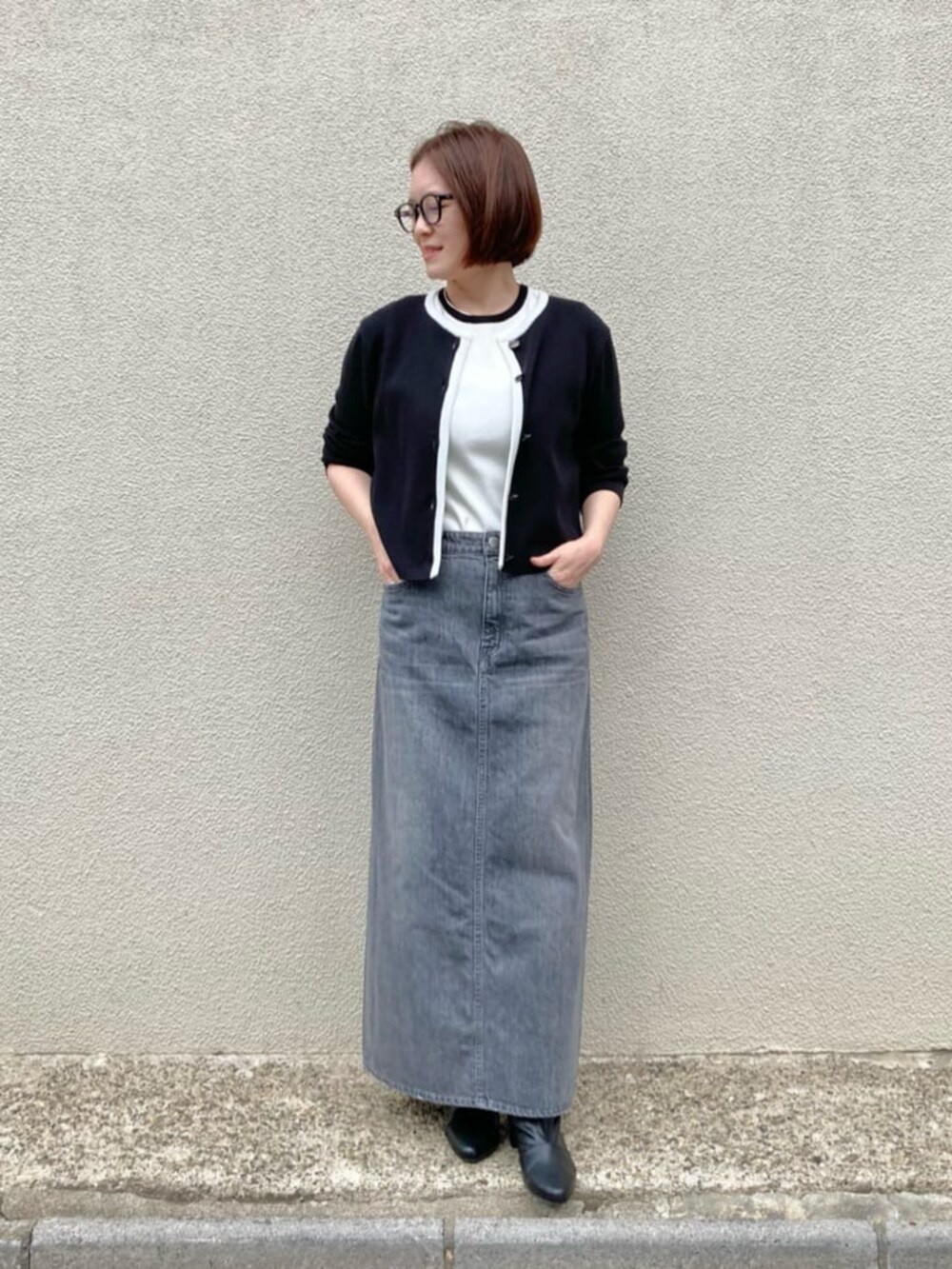 ホワイト系のニット/セーター、ブラック系のカーディガン/ボレロ、グレー系のスカートを着用したレディースの秋コーディネートの4枚目の写真