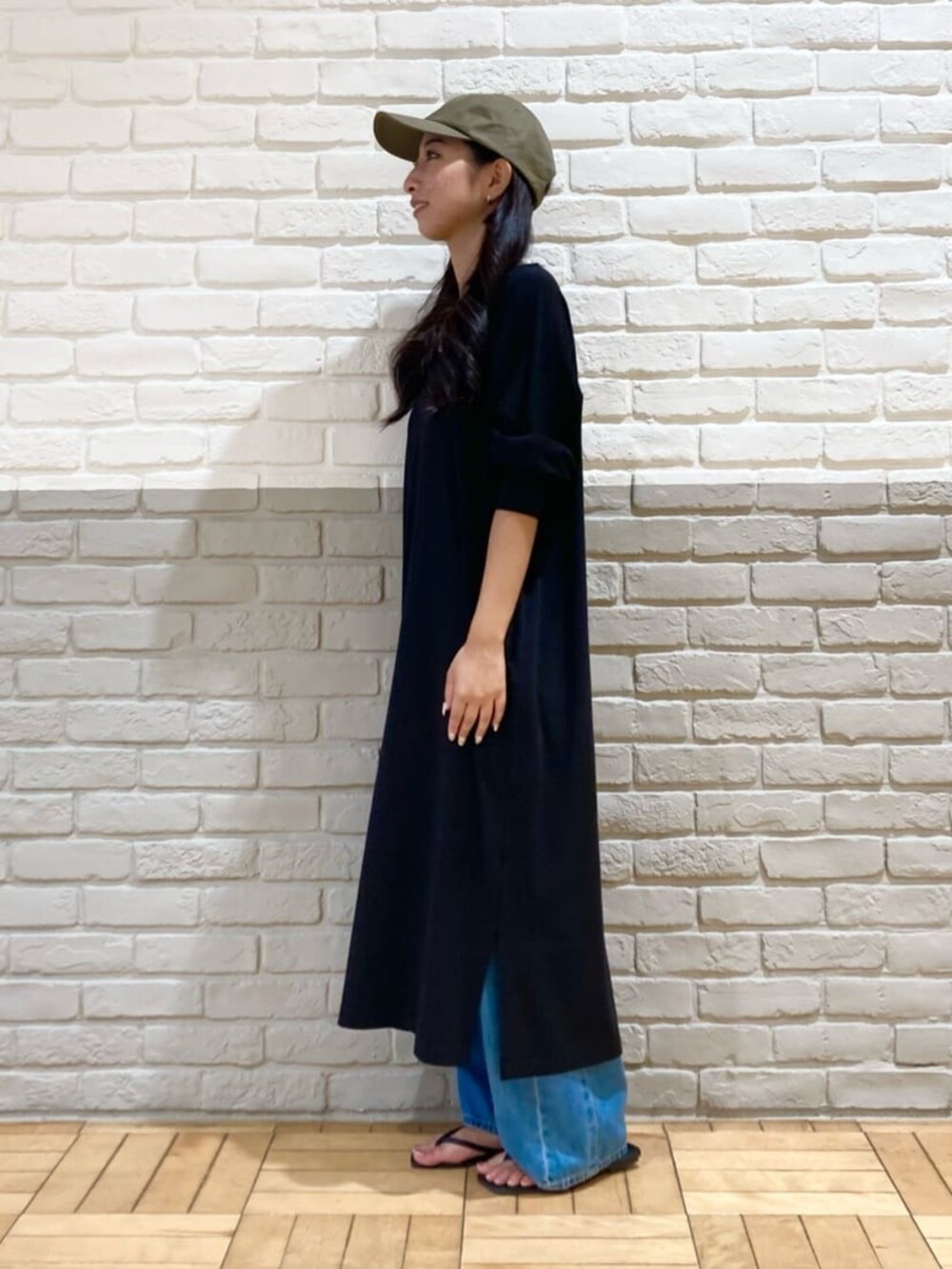 ブラック系のワンピース、ブルー系のデニムパンツ、グリーン系のキャップを着用したレディースの秋コーディネートの3枚目の写真