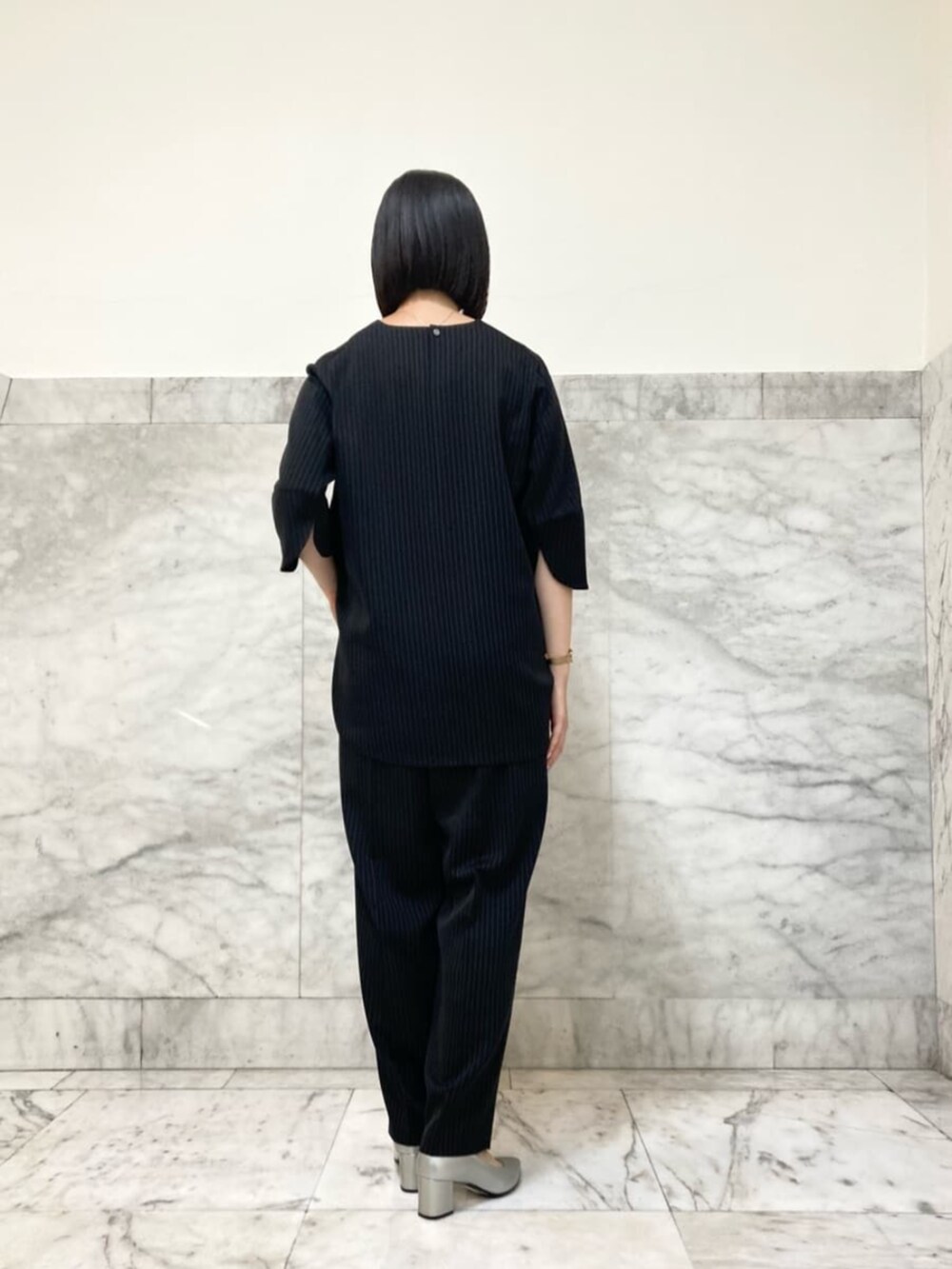 グレー系のシャツ/ブラウス、ブラック系のスラックスを着用したレディースの夏コーディネートの2枚目の写真