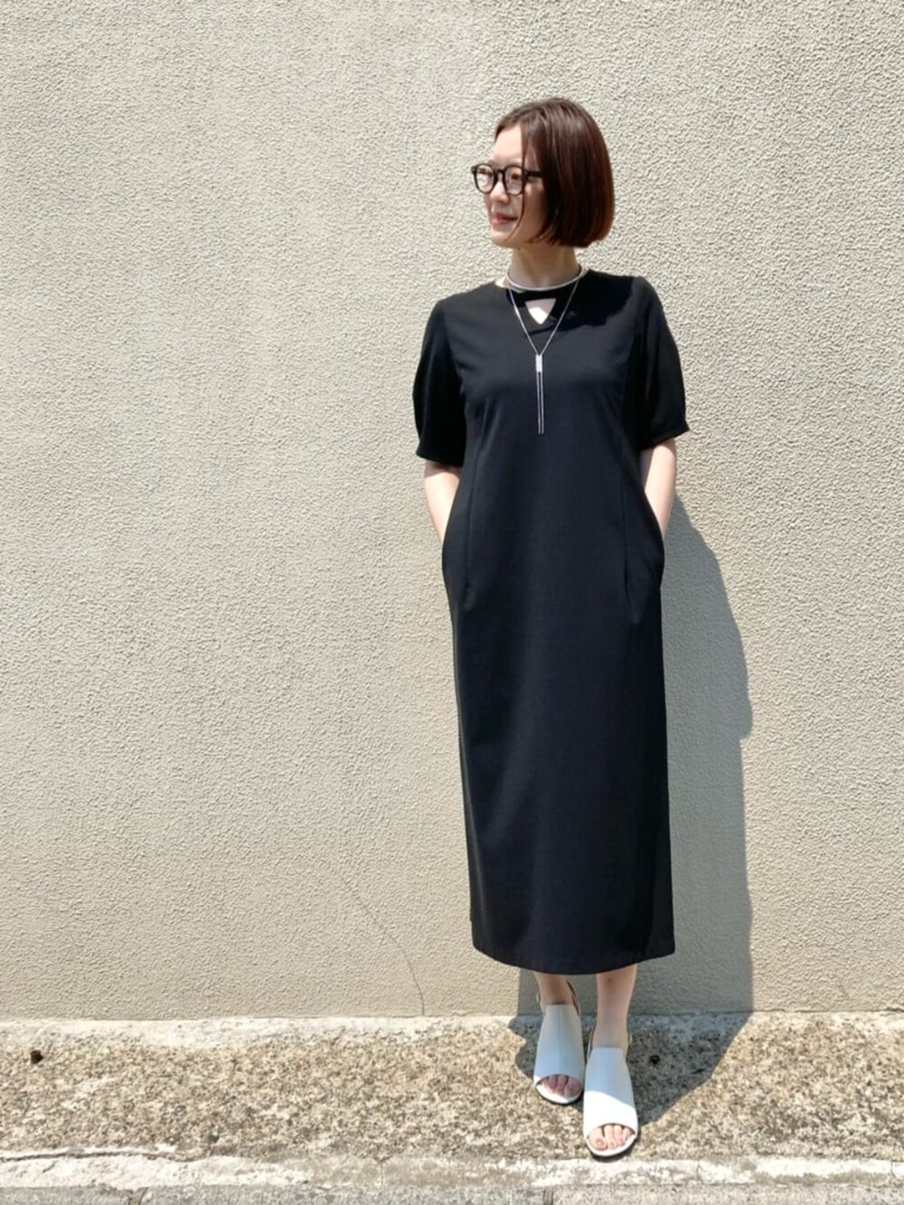 ホワイト系のサンダル、ブラック系のワンピース、シルバー系のネックレスを着用したレディースの春コーディネートの3枚目の写真