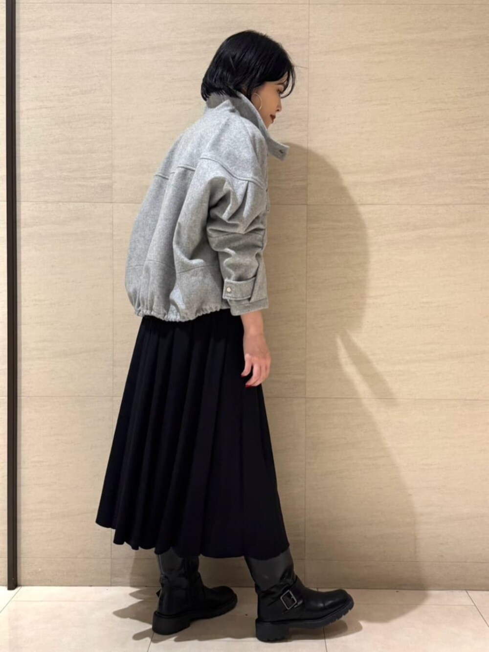 グレー系のブルゾン、ブラック系のTシャツ/カットソー、ブラック系のスカートを着用したレディースの冬コーディネートの4枚目の写真