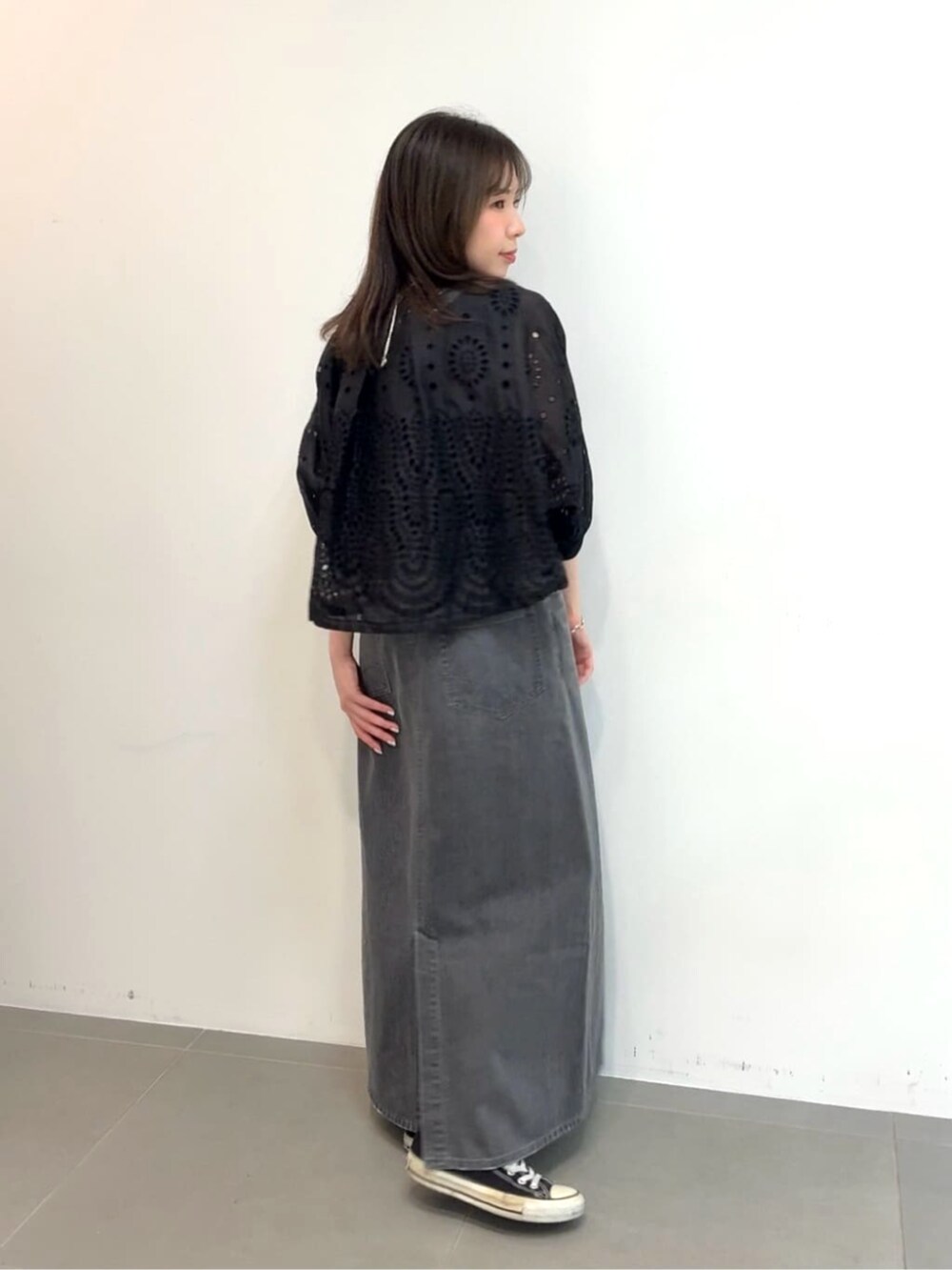 グレー系のスカート、ブラック系のタンクトップ、ブラック系のブルゾンを着用したレディースの夏コーディネートの3枚目の写真