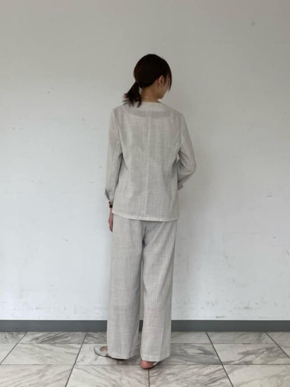 ホワイト系のキャミソール、ホワイト系のノーカラージャケット、ホワイト系のスラックスを着用したレディースの夏コーディネートの2枚目の写真