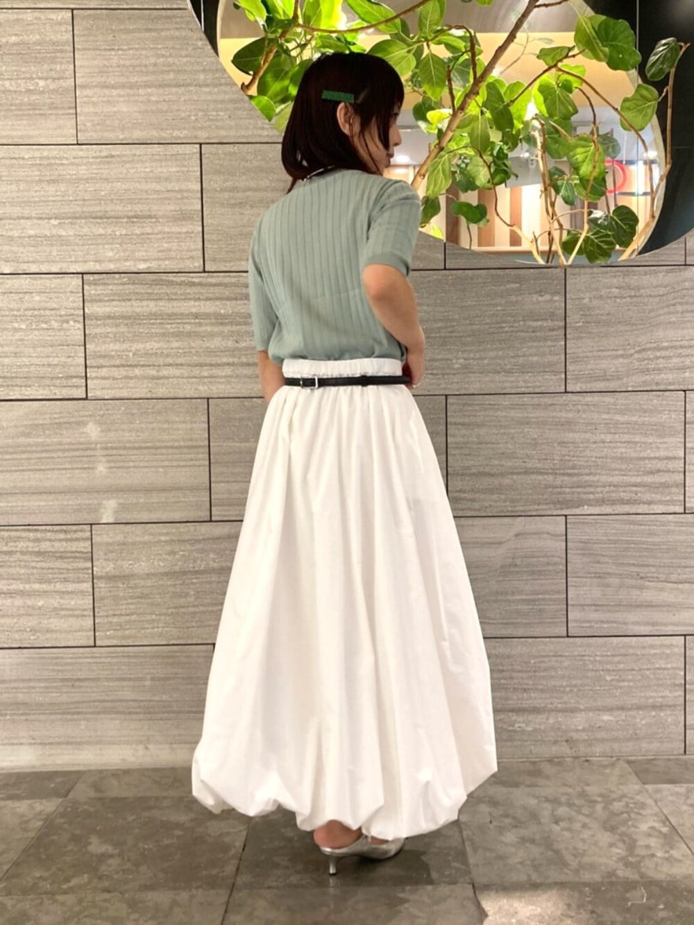 グリーン系のニット/セーター、ホワイト系のスカートを着用したレディースの春コーディネートの3枚目の写真