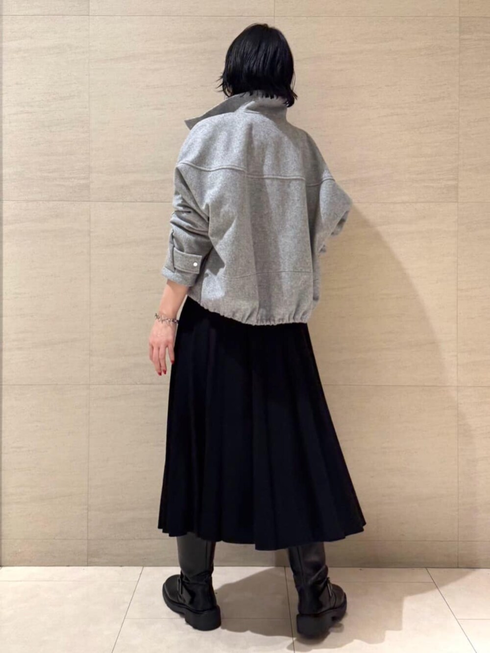 グレー系のブルゾン、ブラック系のTシャツ/カットソー、ブラック系のスカートを着用したレディースの冬コーディネートの5枚目の写真