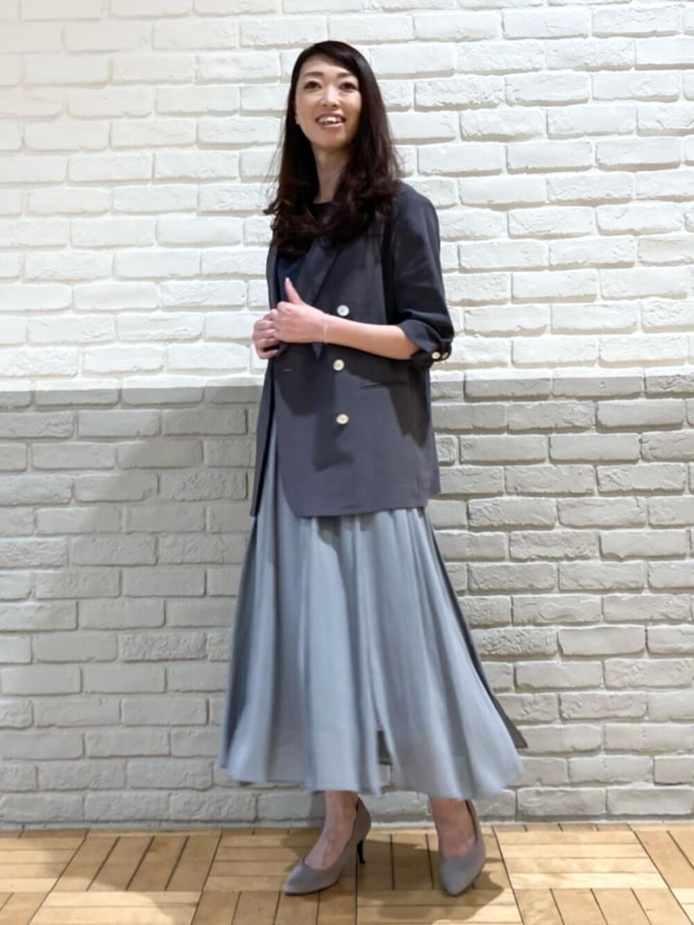 グレー系のテーラードジャケット、グリーン系のスカート、ブラック系のタンクトップを着用したレディースの春コーディネートの2枚目の写真