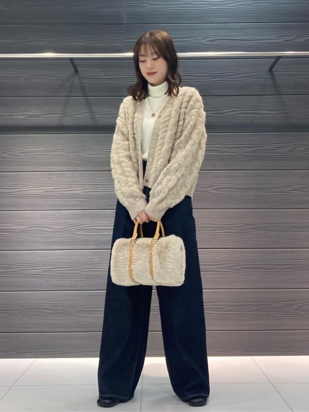 ブルー系のデニムパンツ、ブラック系のブーツ、ベージュ系のカーディガン/ボレロを着用したレディースの冬コーディネートの2枚目の写真