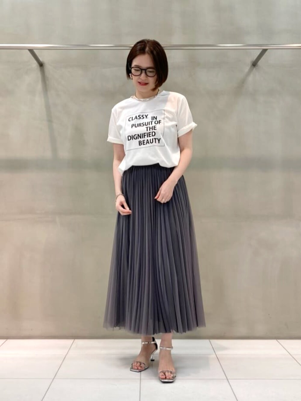 ブルー系のスカート、ホワイト系のTシャツ/カットソー、ブラック系のベストを着用したレディースの春コーディネートの5枚目の写真