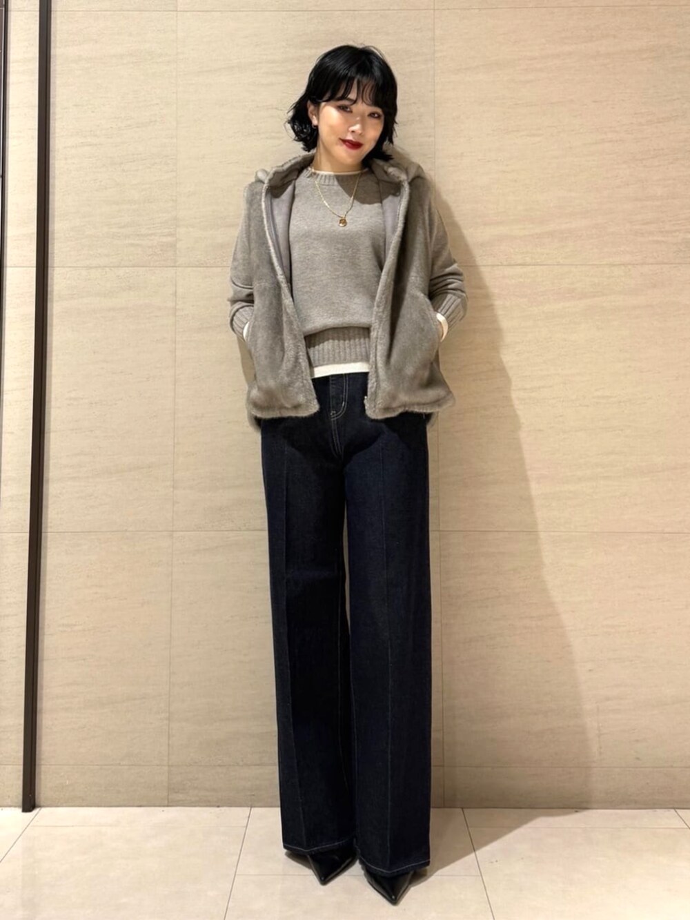 ブルー系のデニムパンツ、ベージュ系のベスト、ブラウン系のニット/セーターを着用したレディースの秋コーディネートの2枚目の写真