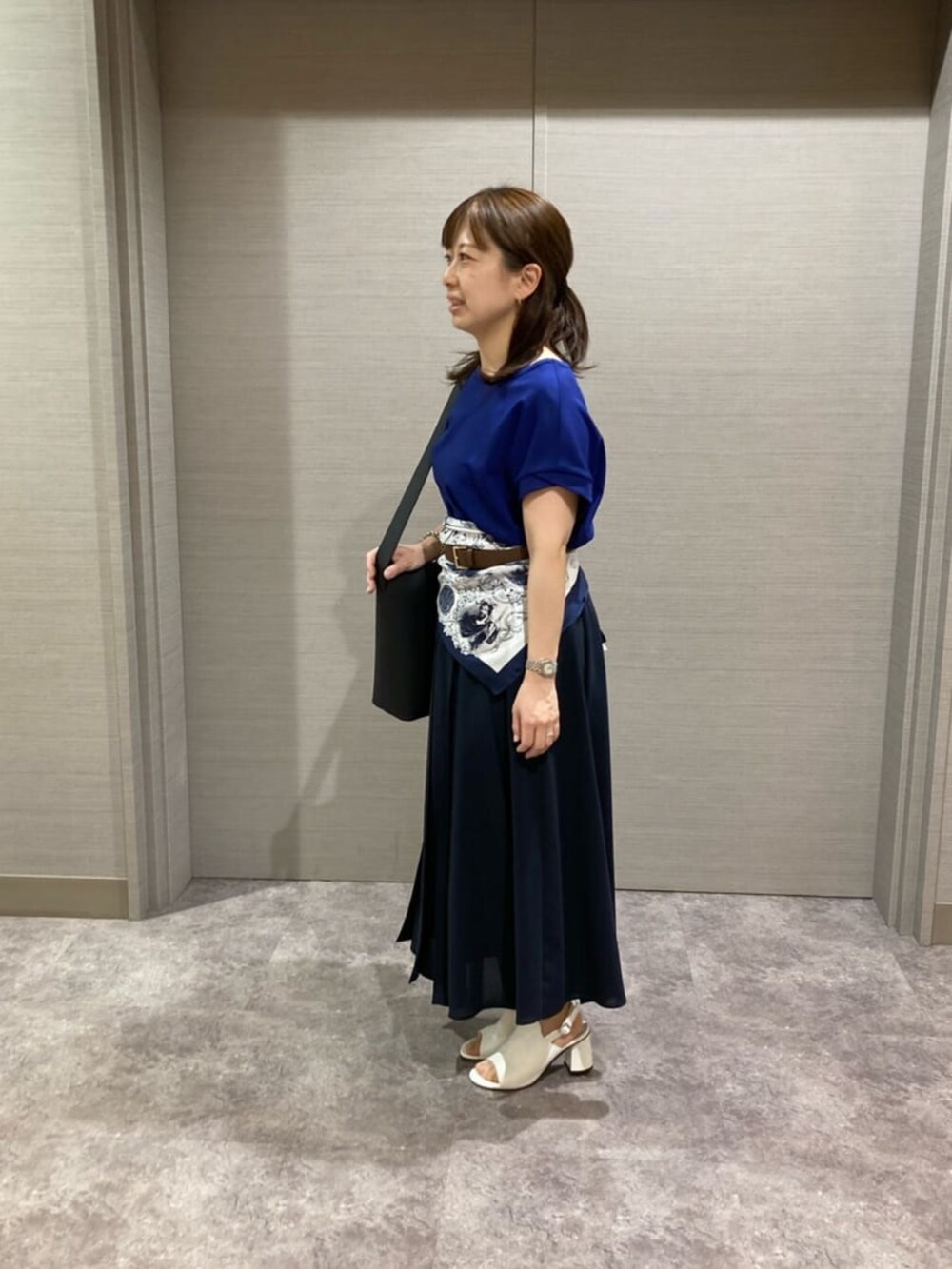 ホワイト系のショルダーバッグ、ブルー系のスカート、ホワイト系のサンダルを着用したレディースの夏コーディネートの2枚目の写真