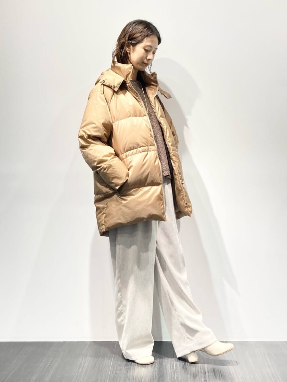 イエロー系のダウンジャケット/コート、ベージュ系のその他パンツ、ホワイト系のブーツを着用したレディースの秋コーディネートの4枚目の写真