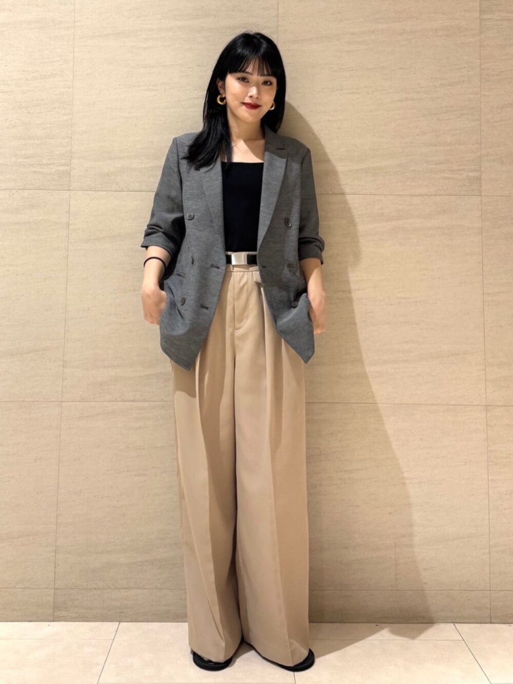 グレー系のテーラードジャケット、ベージュ系のパンツ、ブラック系のベルトを着用したレディースの夏コーディネートの2枚目の写真