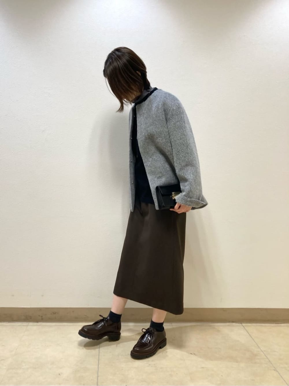 グレー系のその他アウター、ブラック系のスカートを着用したレディースの冬コーディネートの2枚目の写真