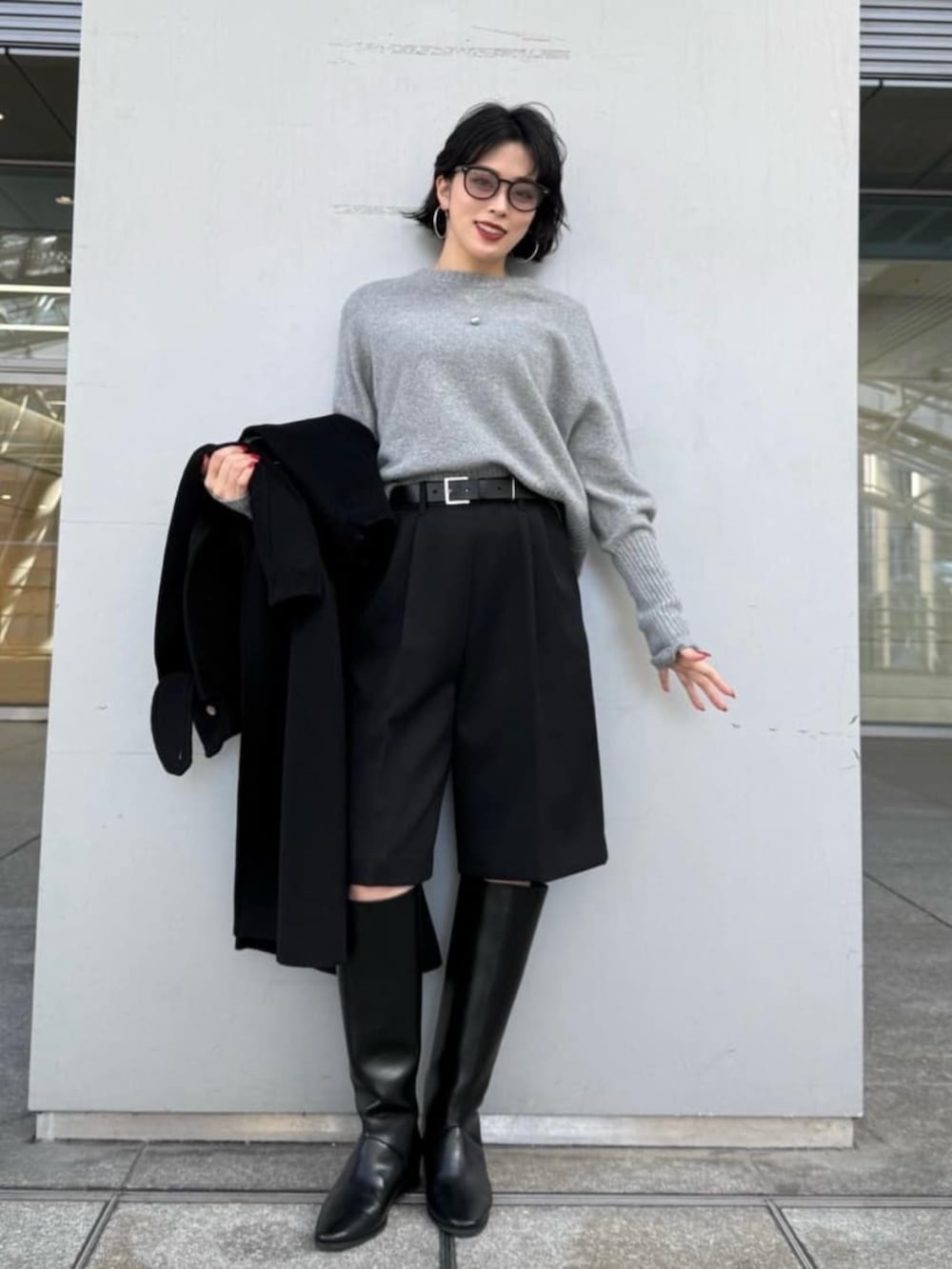ブラック系のトレンチコート、グレー系のニット/セーターを着用したレディースの冬コーディネートの3枚目の写真
